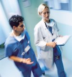 A nurse and doctor are walking down a hallway.